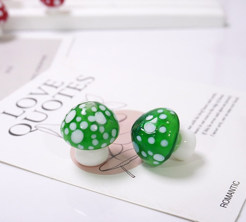 Two green mushroom-shaped glass beads with white dots on a LOVE QUOTES card