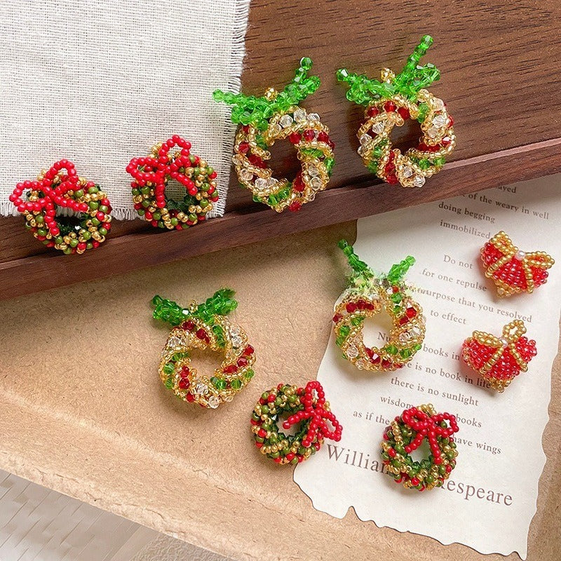 Small beaded Christmas wreath ornaments in red, green, and gold seed beads on a wooden tray