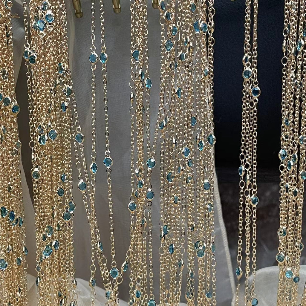 Gold chain fringe curtains with small blue faceted gemstones hanging in multiple strands.