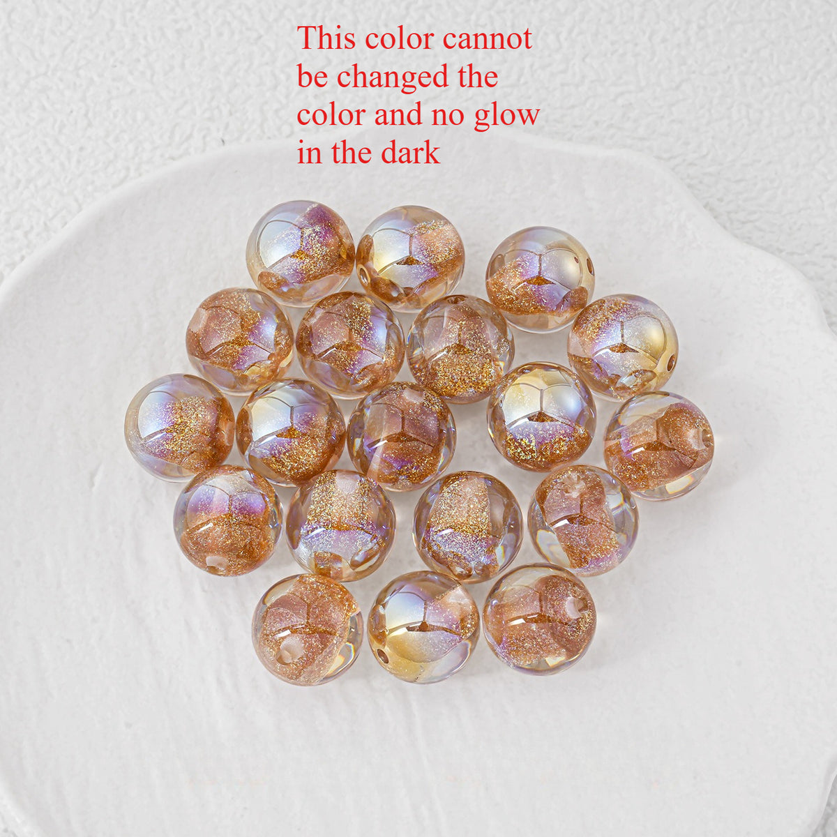 Cluster of round resin beads with metallic gold glitter pattern and iridescent finish on a white plate.
