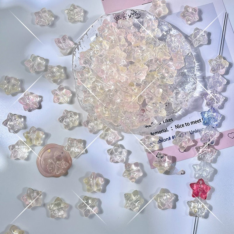 Small translucent pastel star-shaped glass beads in pink, yellow, and clear on white