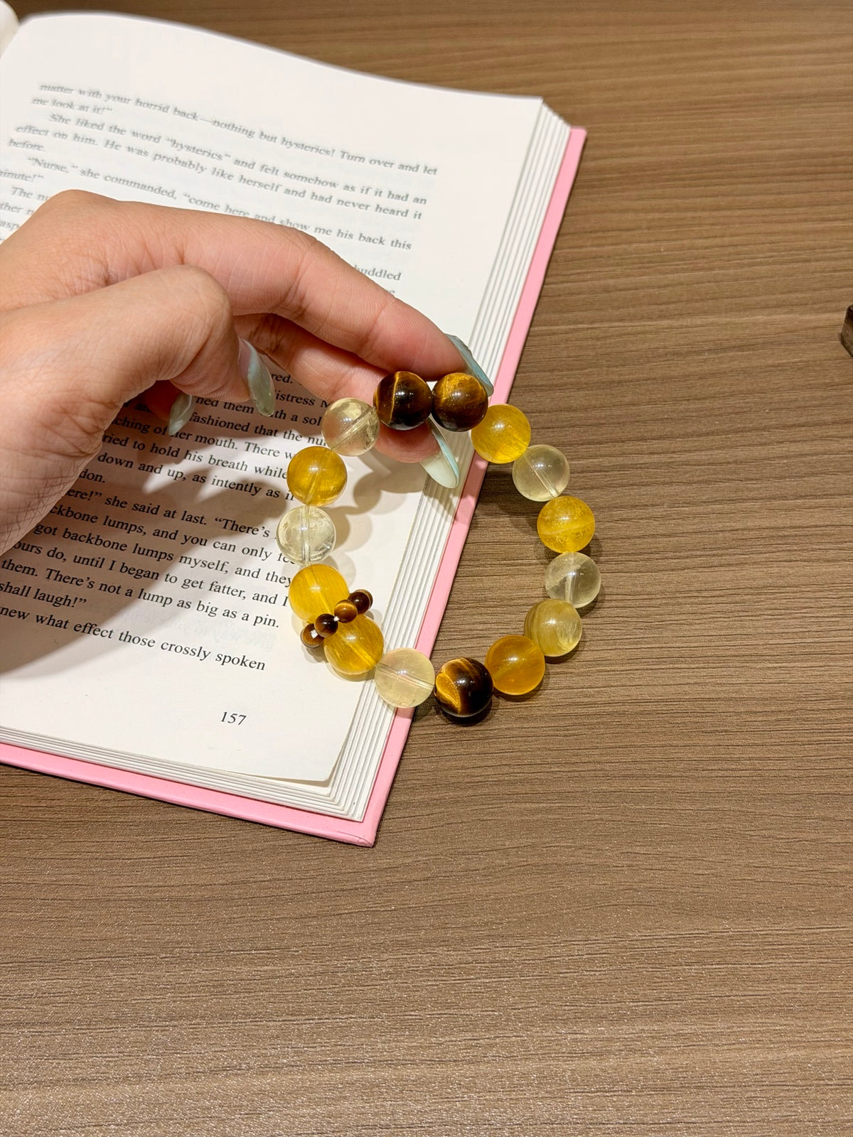 Hand holding golden wind citrine bracelet over open book