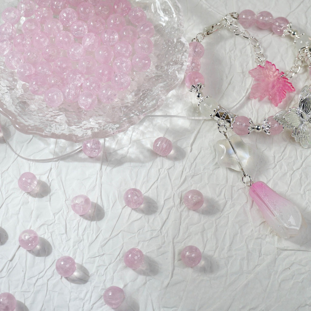 Pink glass bead bracelets with charms beside a bowl of loose pink beads