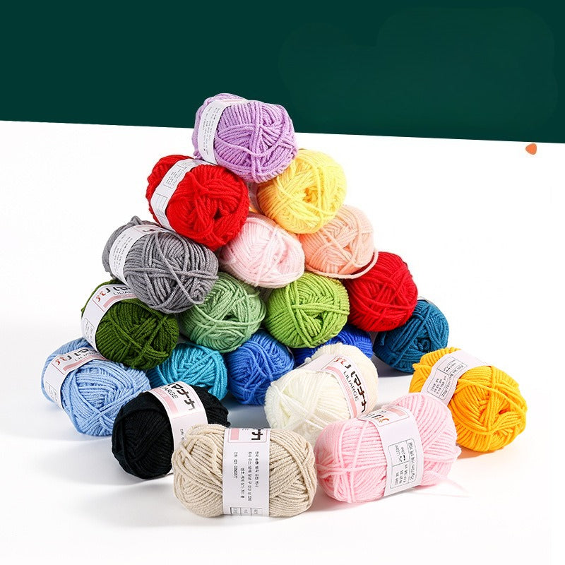 A pyramid arrangement of colorful yarn balls in multiple shades including red, purple, yellow, pink, gray, green, blue, black, beige, and orange, displayed on a white surface with a dark green background.