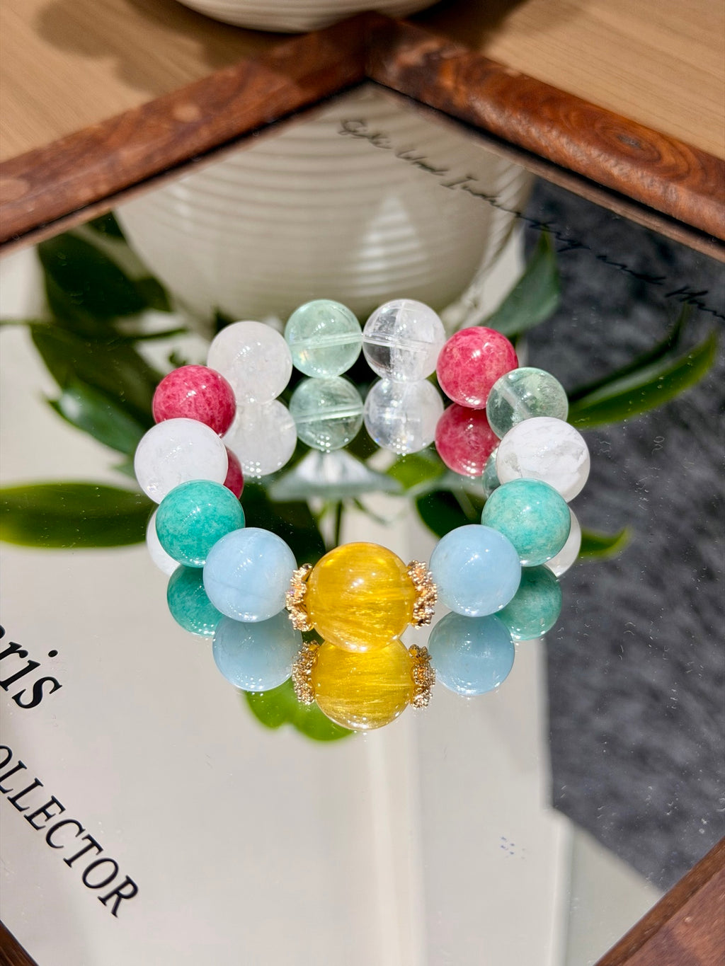 Woven Sea Reverie bracelet reflected in a mirror with green leaves