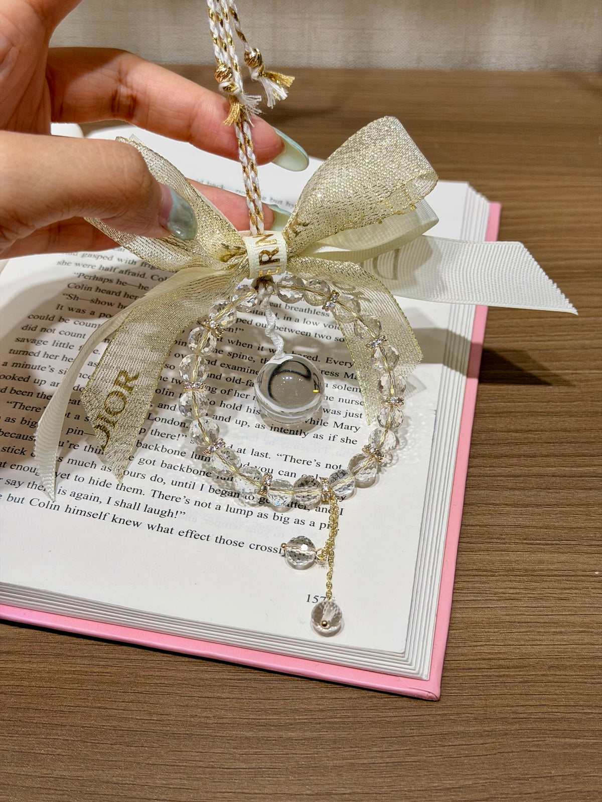 Starlight Dewdrop white crystal car hanging with gold bow held in hand