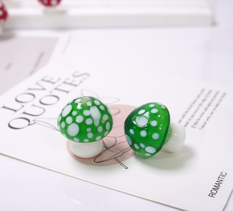 Pair of glossy green mushroom glass beads with white dots on LOVE QUOTES card