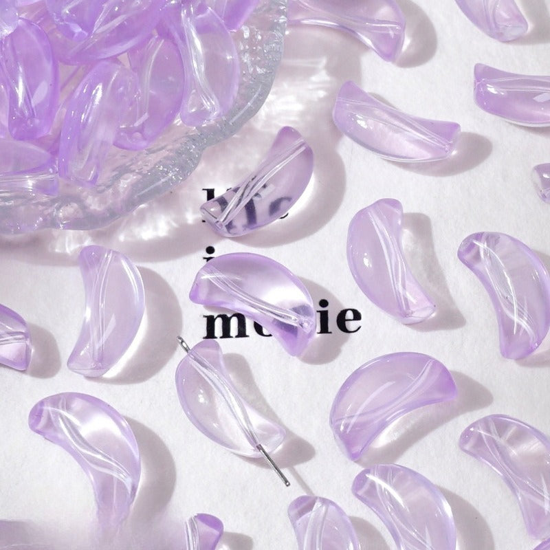 Light purple translucent crescent glass beads on white with a dish and decorative text