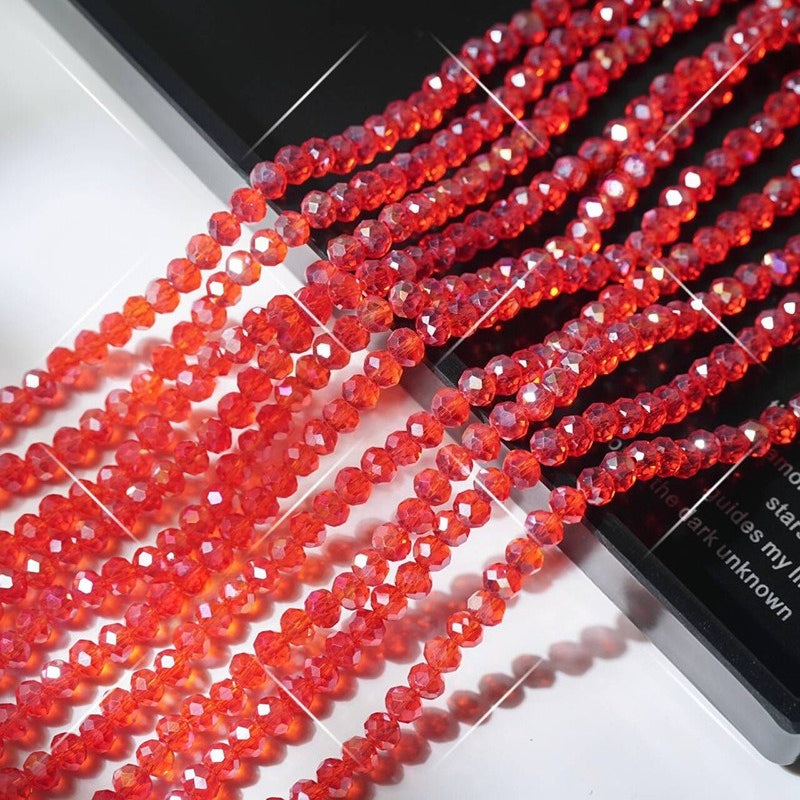 Multiple strands of faceted red crystal glass wheel beads arranged diagonally on white surface