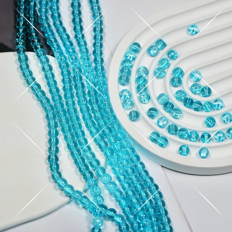 Turquoise faceted glass beads on white display, some draped over side