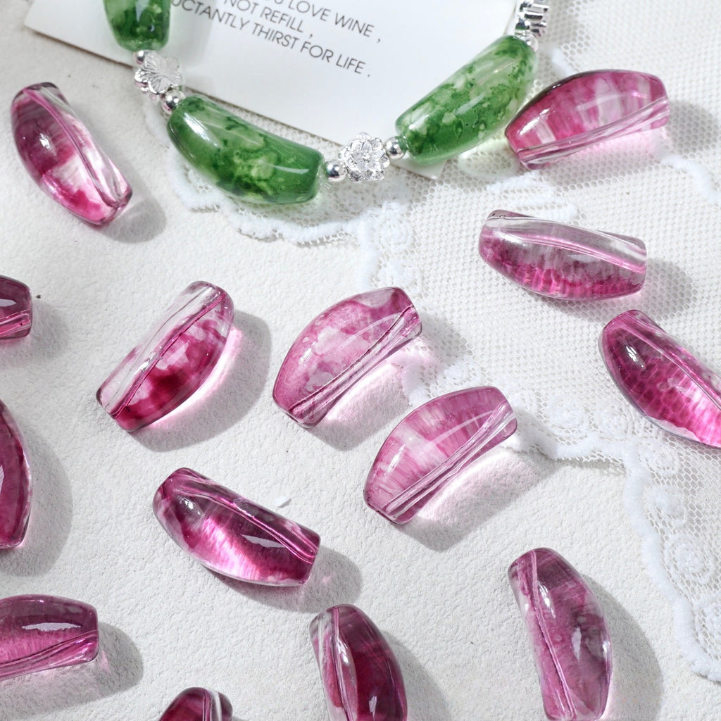 Translucent pink curved glass tube beads with marbling scattered on white lace fabric
