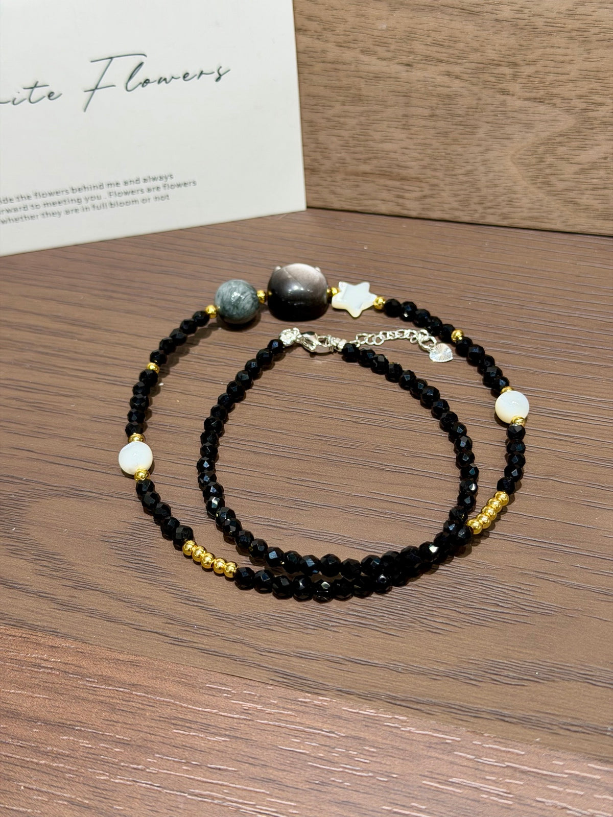 Midnight cat strand with silver obsidian cat head coiled on table