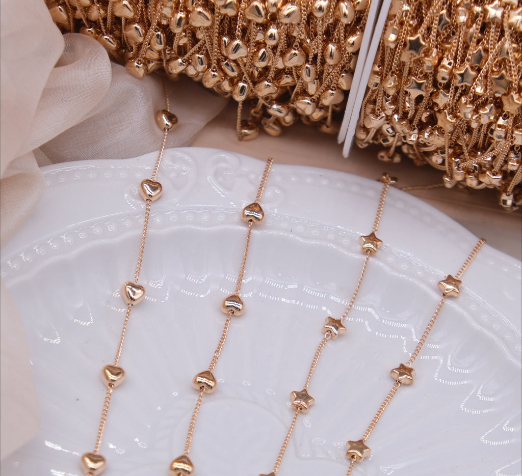 Rose gold chains with alternating heart and star beads draped over a white ceramic plate