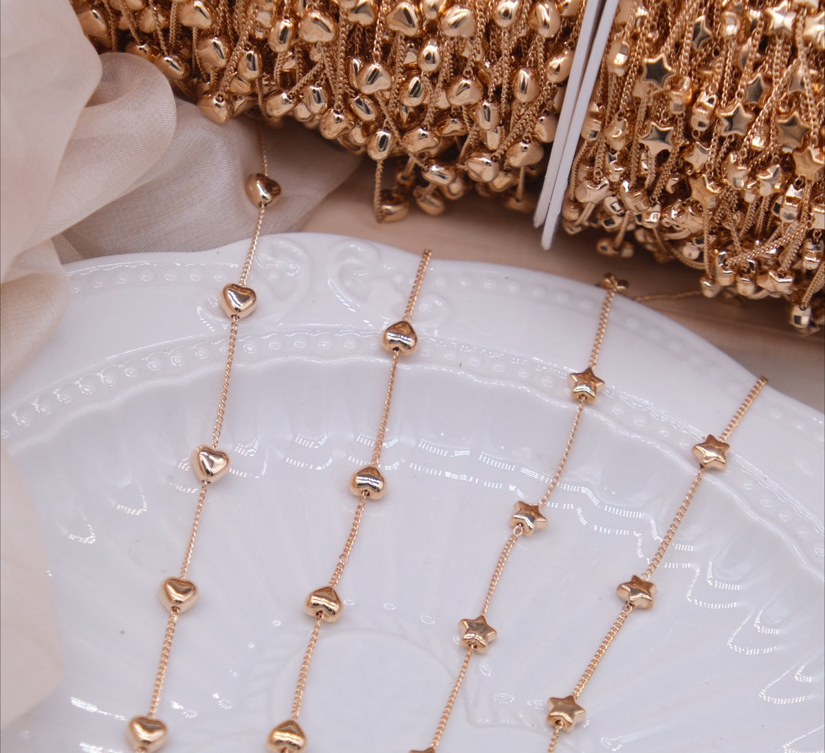 Rose gold chains with alternating heart and star beads draped over a white ceramic plate