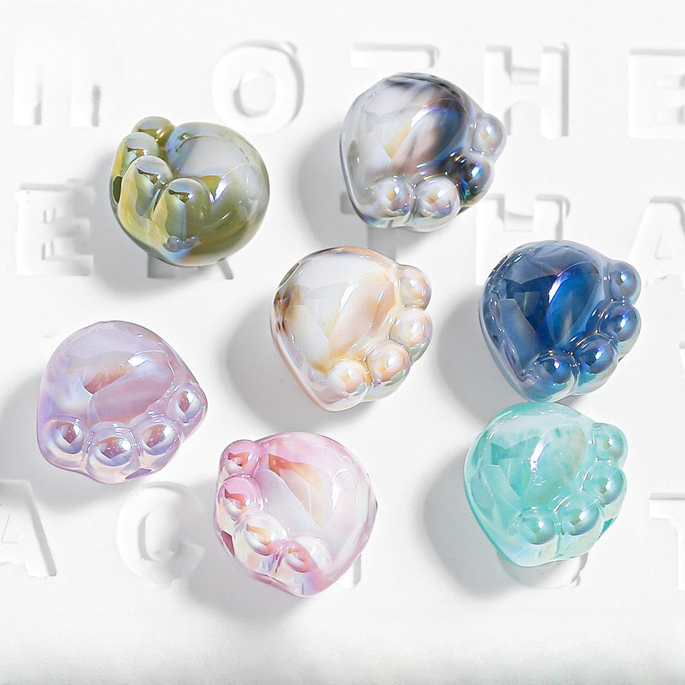 Seven translucent paw-shaped acrylic beads in green, blue, pink and purple