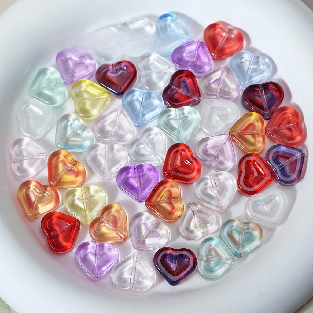 Multicolor translucent heart-shaped glass beads in red, purple, blue, green, yellow and orange arranged in a white dish