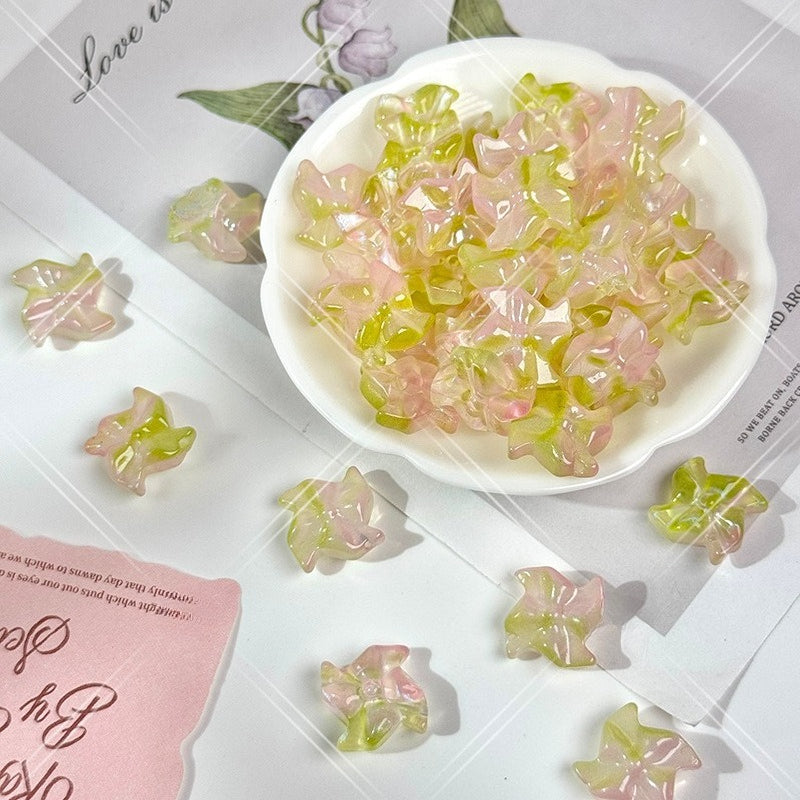 White bowl filled with small translucent soft pink and pale yellow-green 20mm carved glass windmill beads
