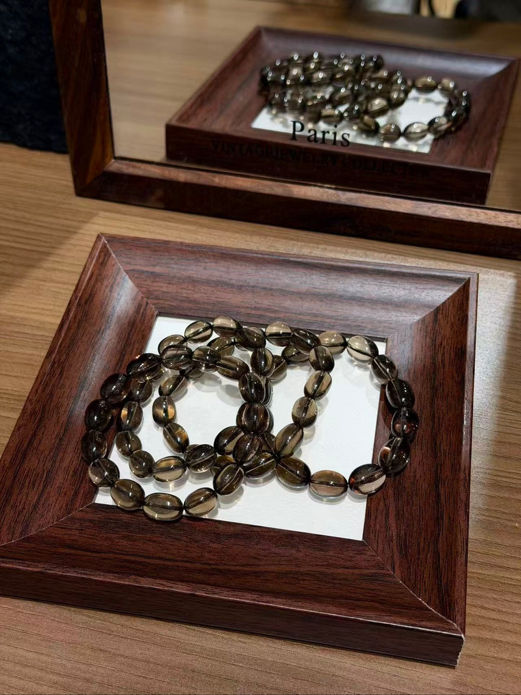 Smoky quartz jelly bean bracelets coiled on a wooden tray