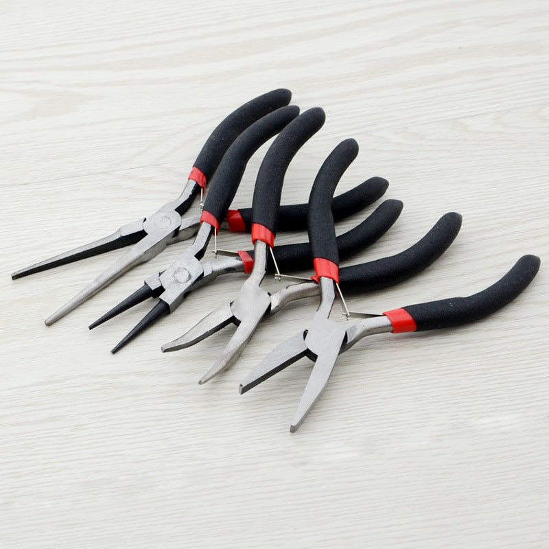 Five pairs of metal wire-nose pliers with black and red handles, arranged diagonally on a light wood-textured surface.