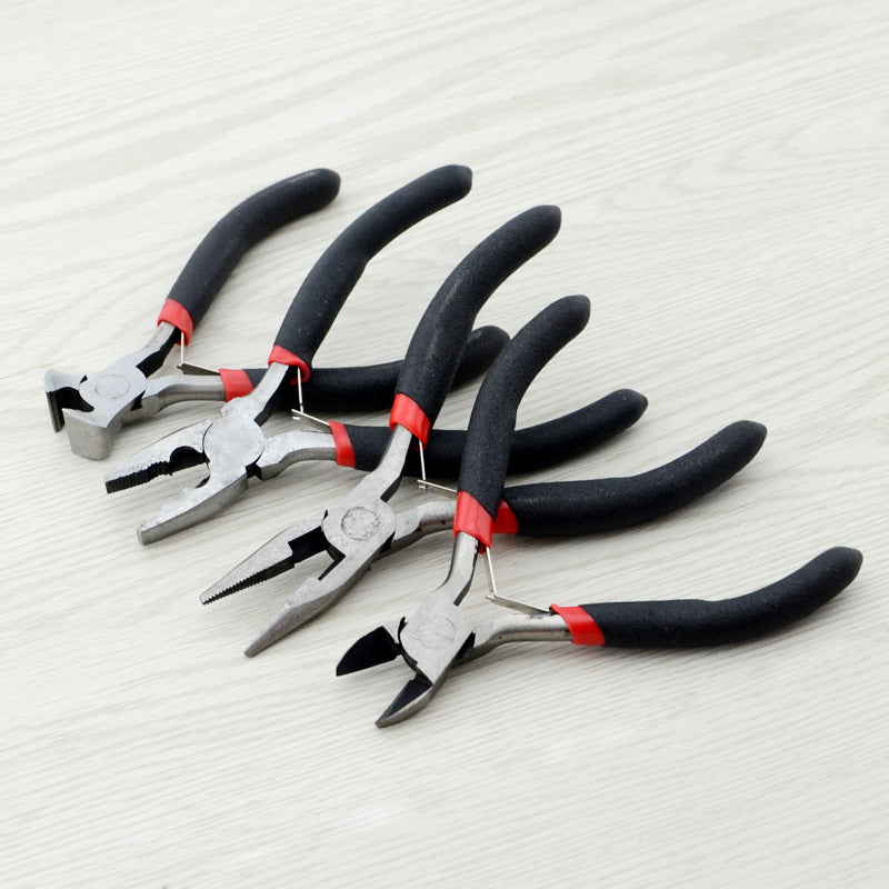 Four pairs of metal pliers with black and red handles arranged diagonally on a light wood surface