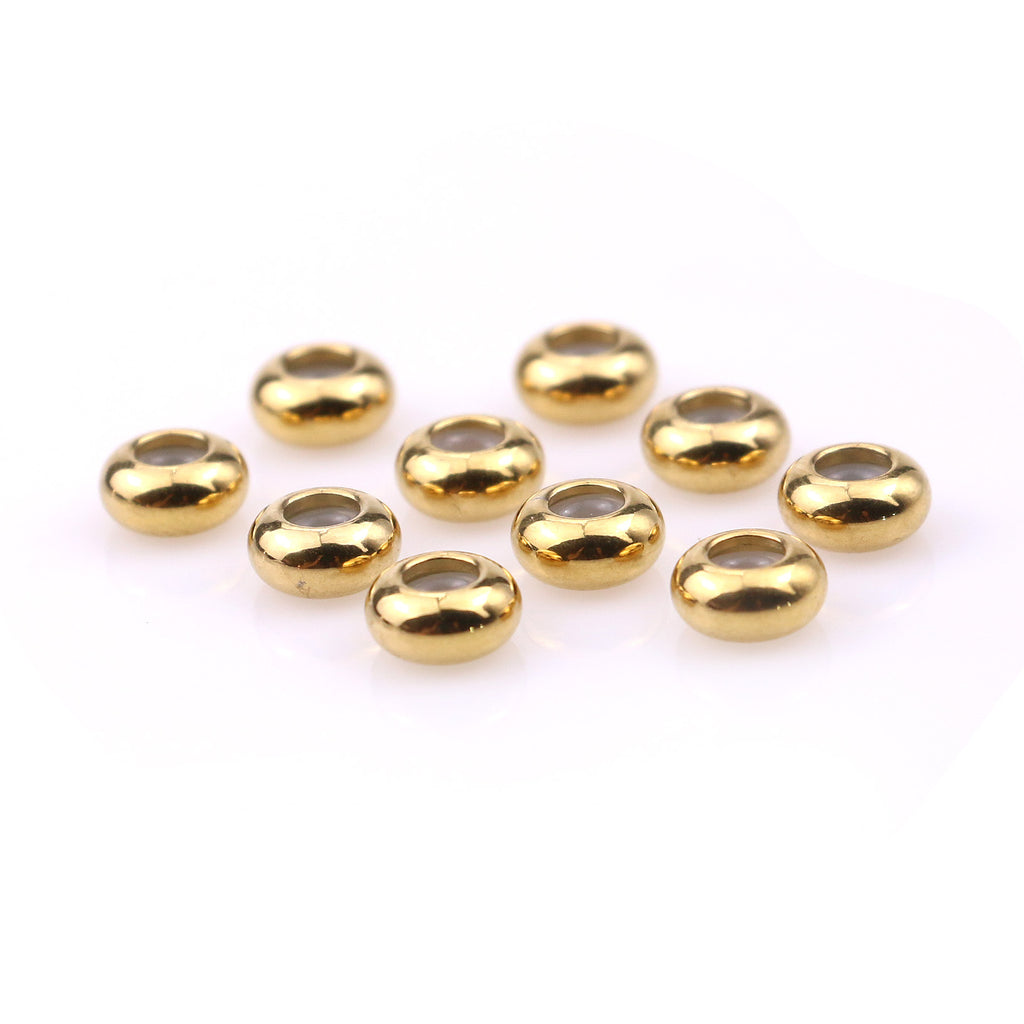 Ten gold stainless steel rounded abacus stopper beads arranged on white, angled view