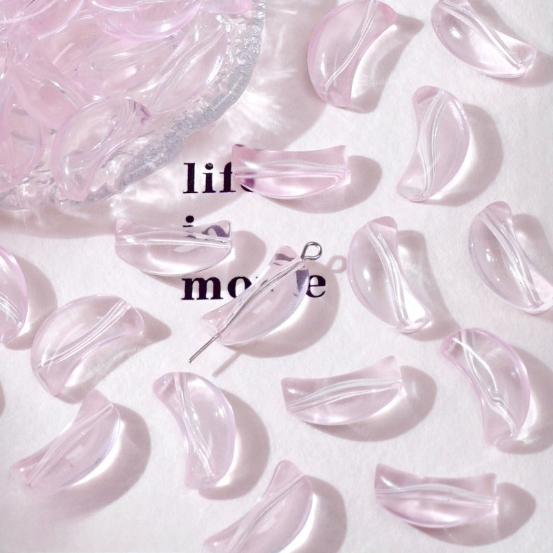Light pink translucent crescent glass beads on white with 'life movie' text and a dish