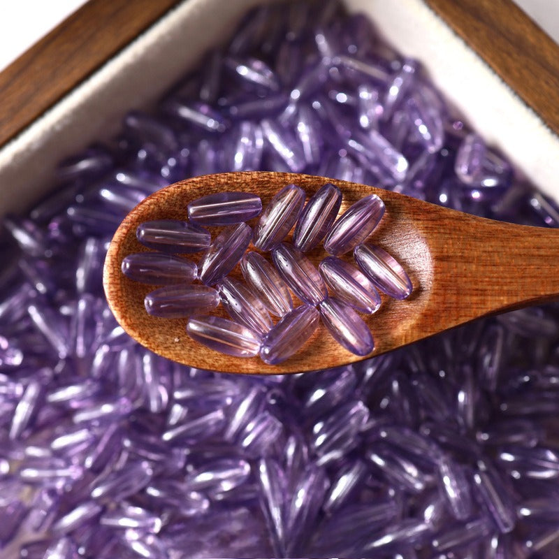 Purple translucent 4x9mm glazed glass long rice beads in a wooden spoon