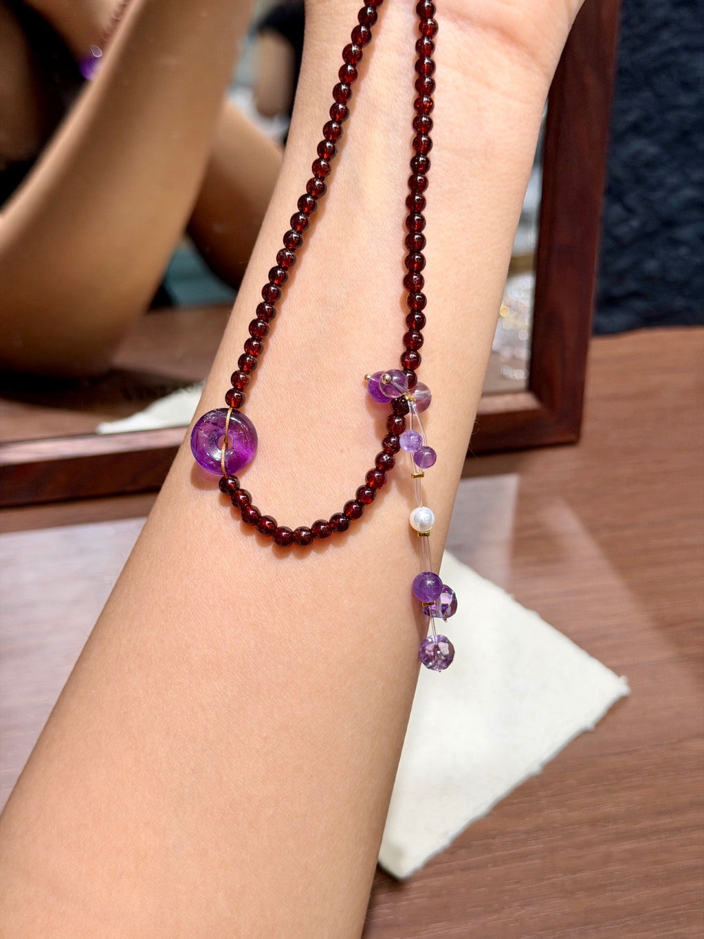 Garnet & Amethyst Peace Buckle Necklace draped on wrist