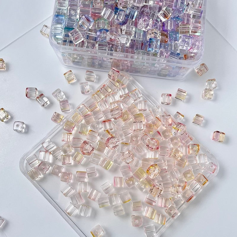 Clear container of pastel pink and peach faceted square glass beads
