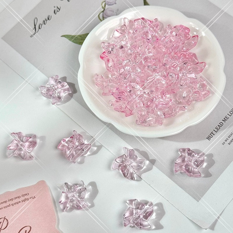 Pink translucent 20mm carved glass windmill beads on a white surface with a white dish and printed paper