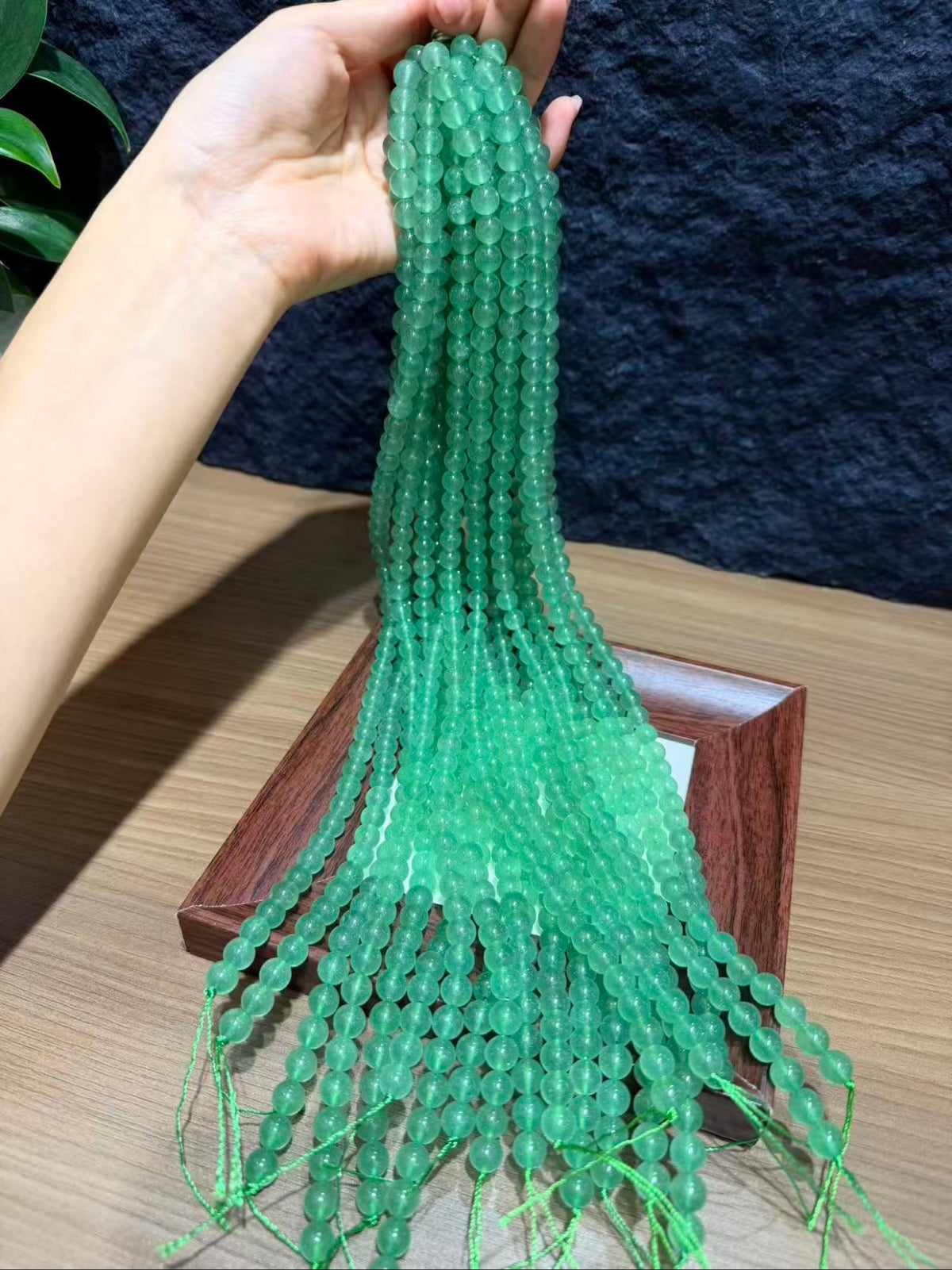 Hand holding a bundle of green strawberry quartz bead strands