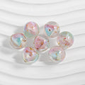 Seven clear resin beads with pastel iridescent swirls and gold foil