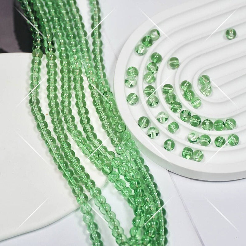 Green faceted glass beads on white display, strands draped on left