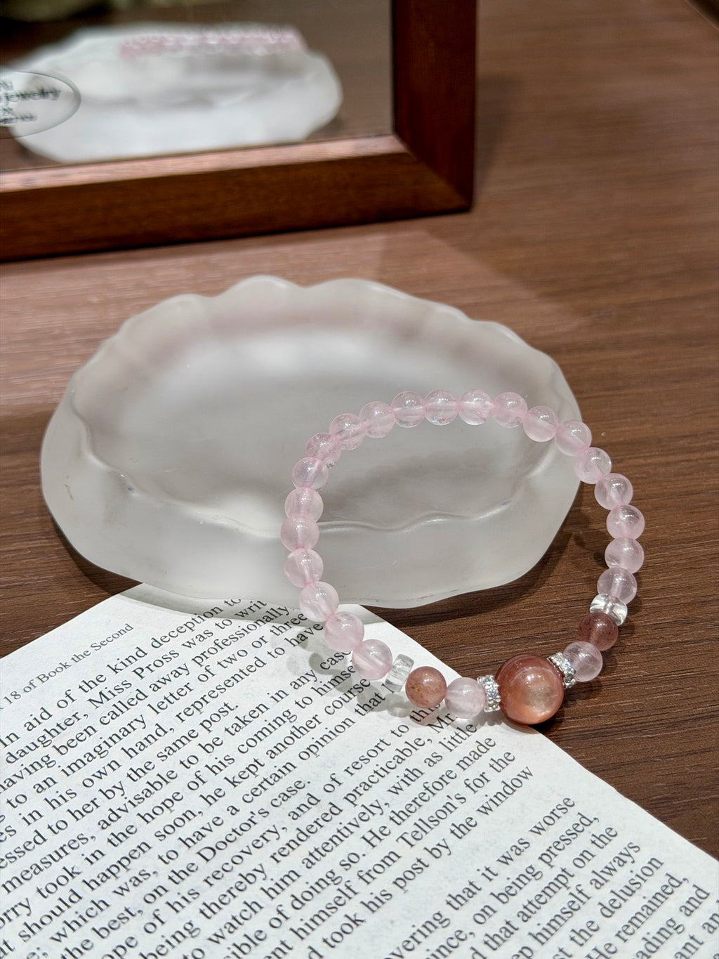 Pink gummy bracelet on shell dish over book