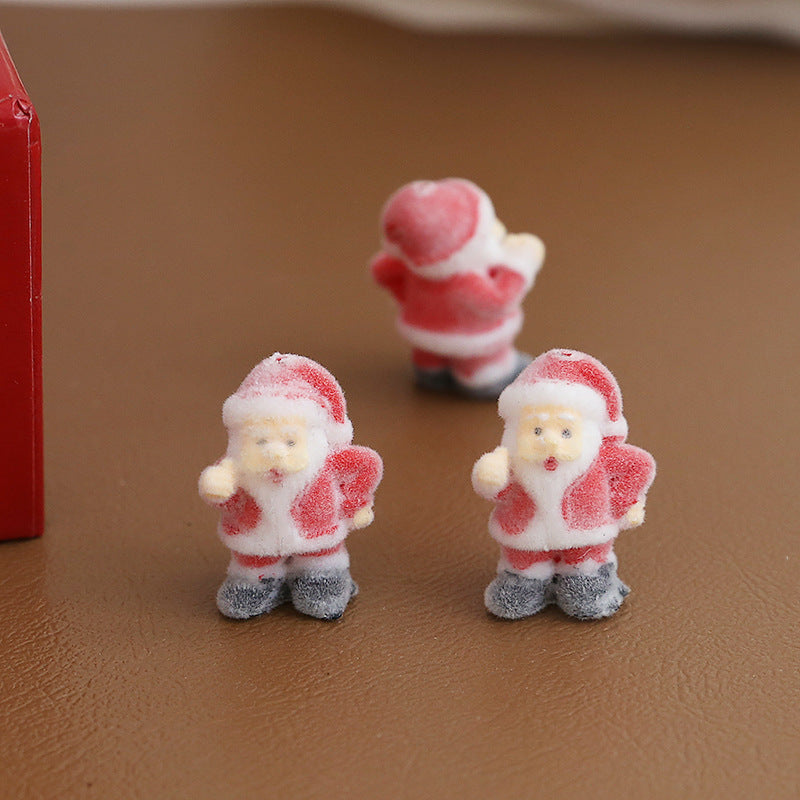 Three small Santa Claus figurines with frosted candy-coated texture standing on brown surface