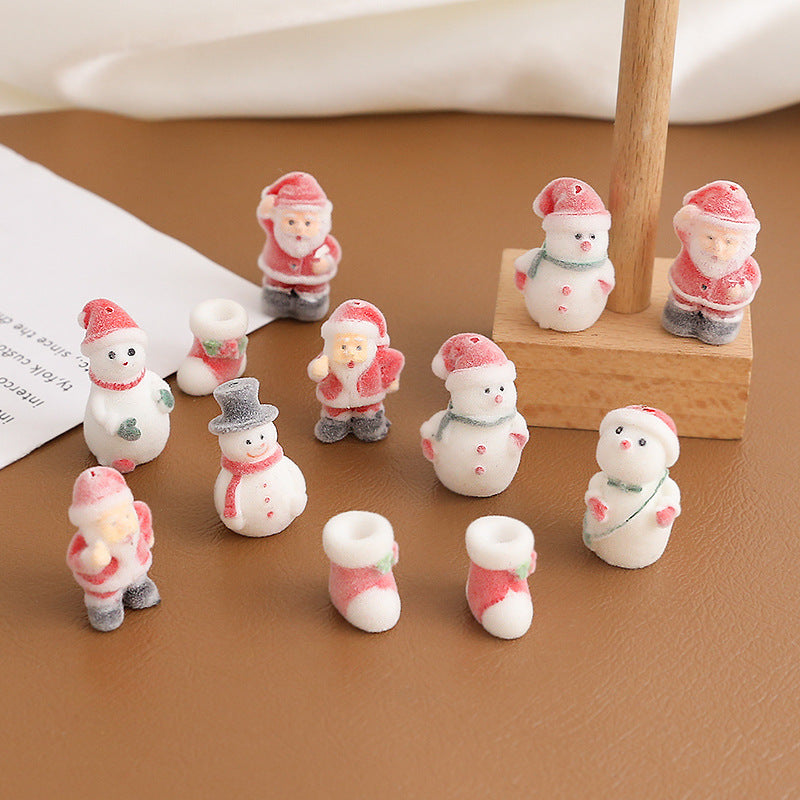 Small Christmas-themed miniature figurines and boot-shaped accessories arranged on brown surface