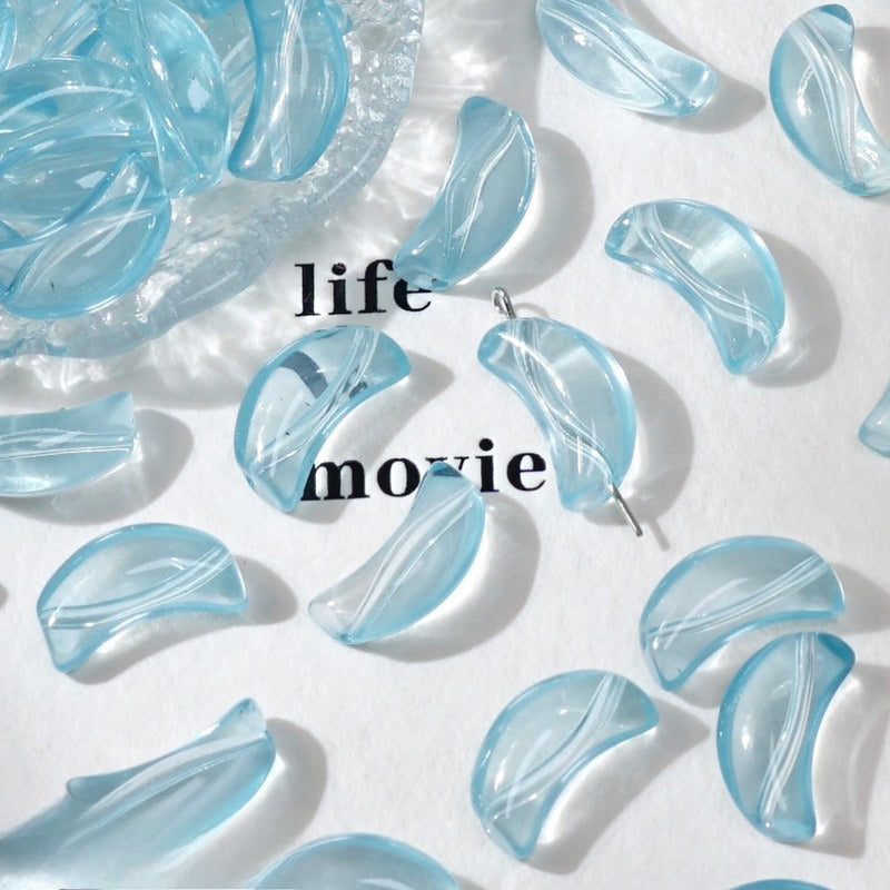 Light blue translucent crescent glass beads on white with 'life movie' text and a dish