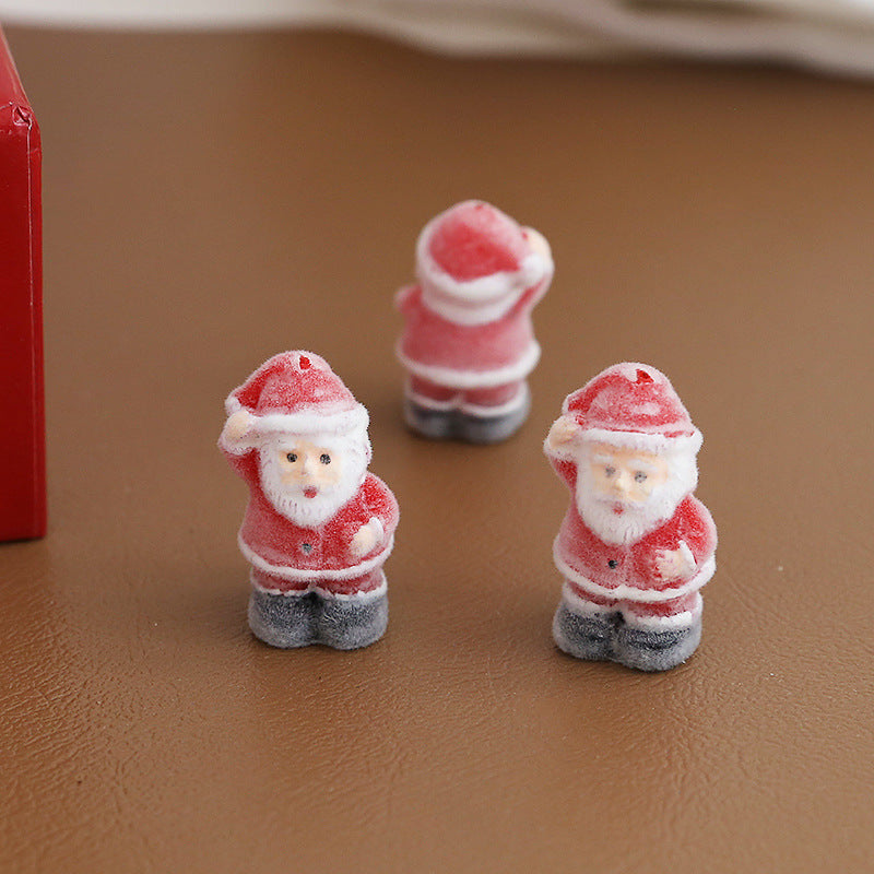 Three small Santa Claus figurines with frosted candy-coated finish standing on brown textured surface