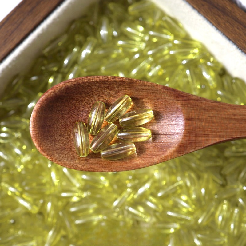 Golden-yellow glazed glass long rice beads in a wooden spoon