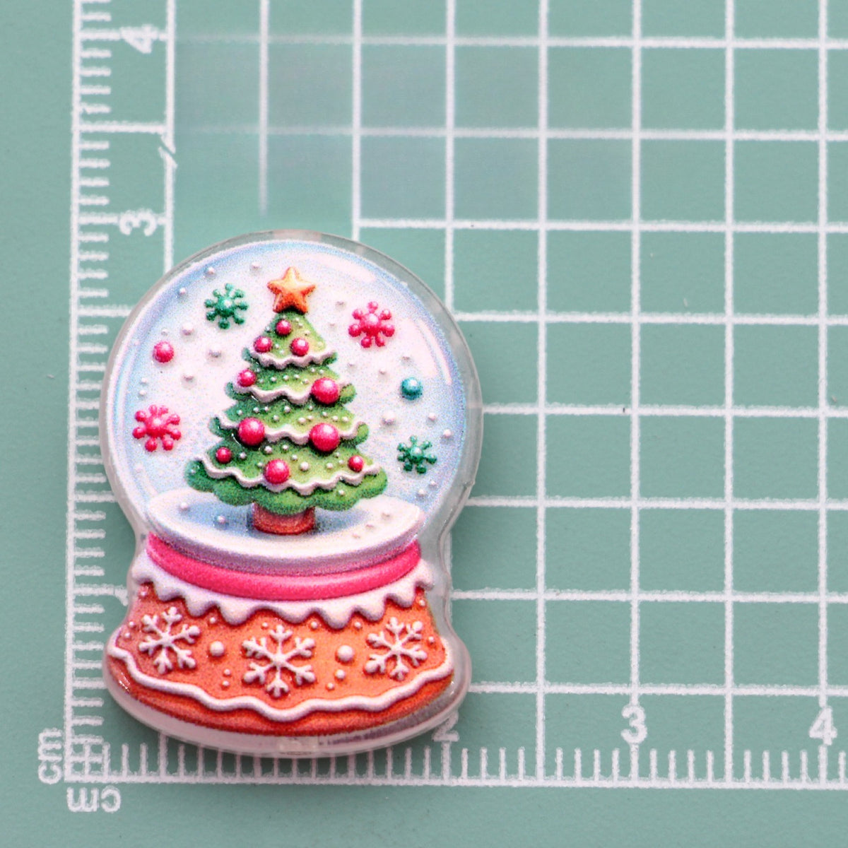 Snow globe acrylic charm with Christmas tree, red ornaments and snowflakes on pink base