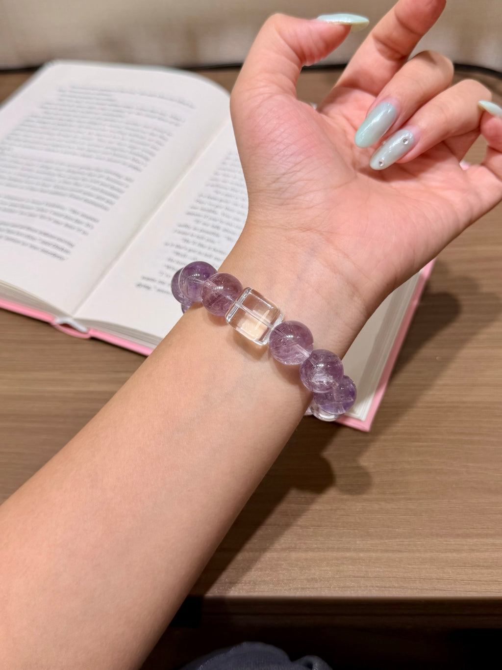 Hand holding purple mist bracelet with snowflake phantom quartz