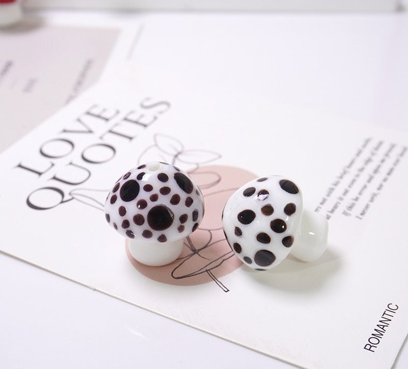 Two white mushroom-shaped glass beads with black spots on a LOVE QUOTES card