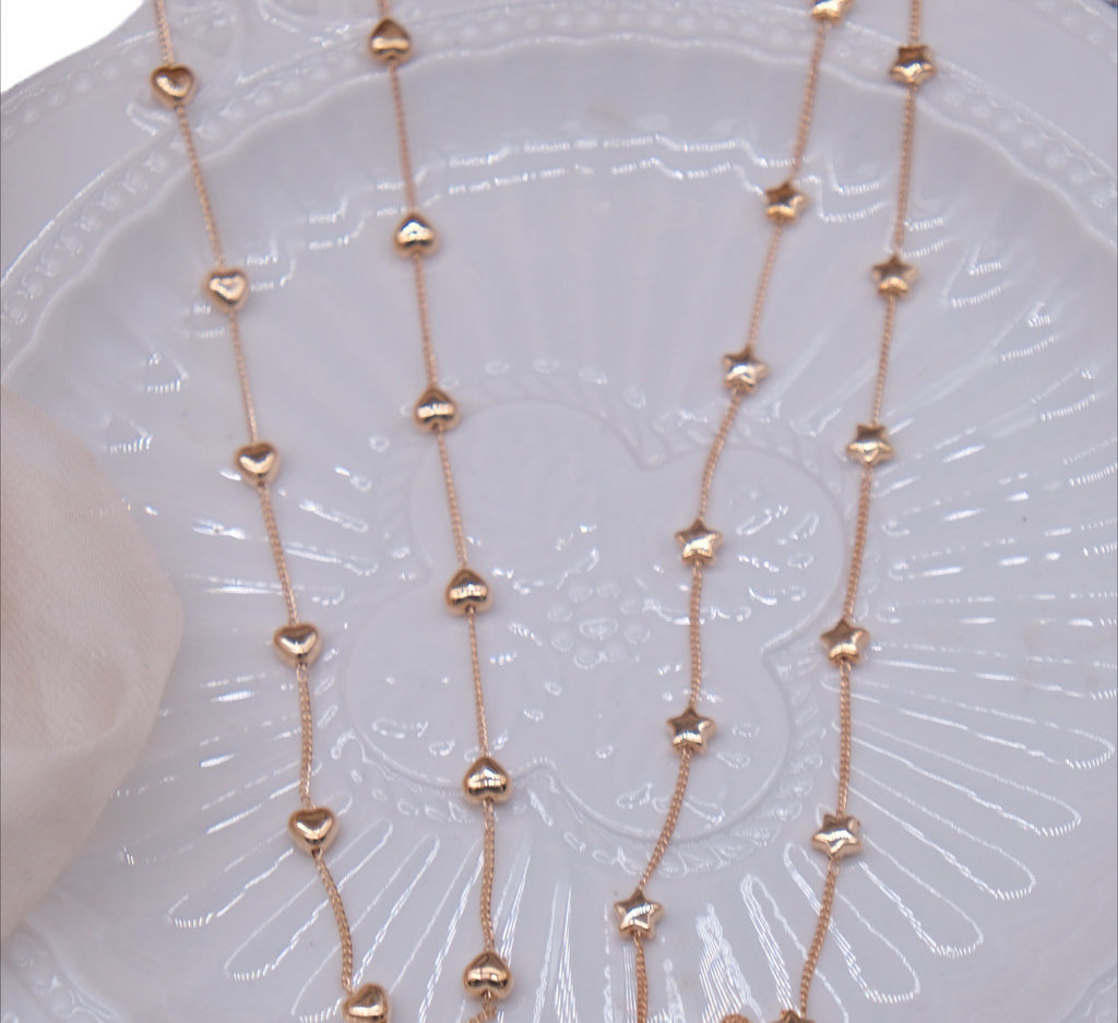 Rose gold heart and star bead chains laid out on a white ceramic plate