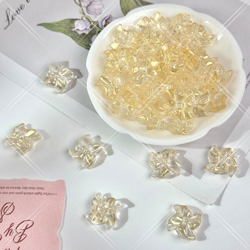 Clear 20mm carved glass windmill beads with a subtle yellow tint on a white surface with a small white dish