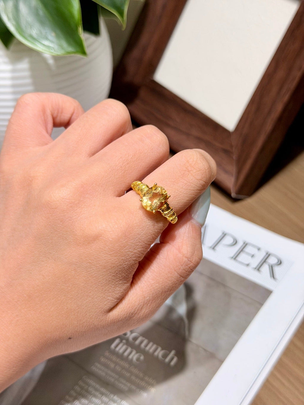 Hand wearing golden citrine solitaire ring with textured gold band