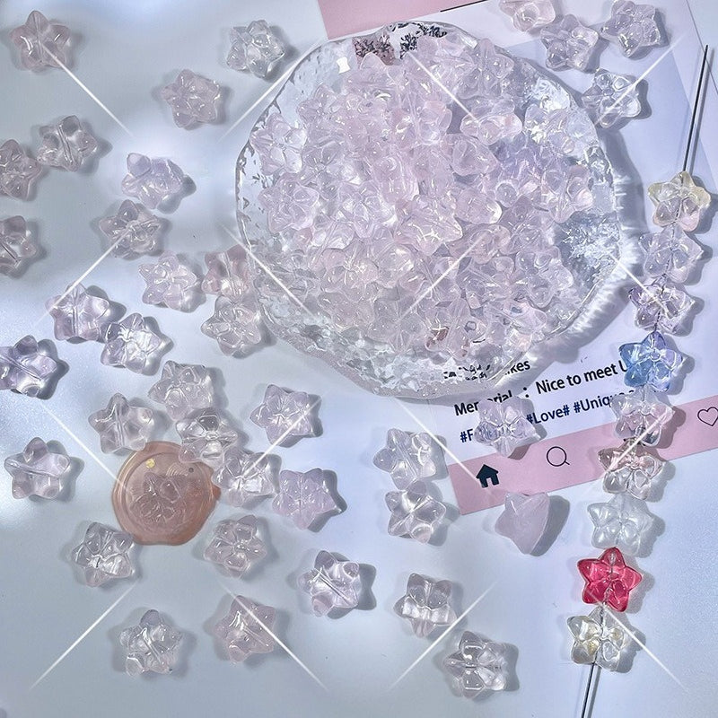 Translucent pastel star-shaped glass beads in pink, purple, and clear on a white surface
