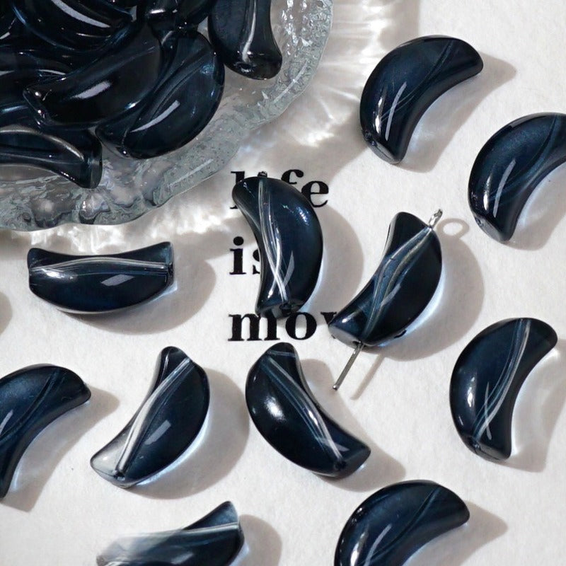Glossy black crescent glass beads on white with 'life is movie' text and a glass dish