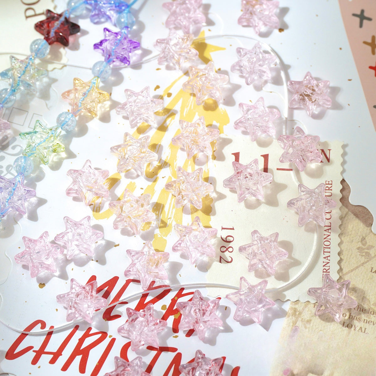 Close-up of translucent star-shaped glass beads in pastel colors scattered on a printed card