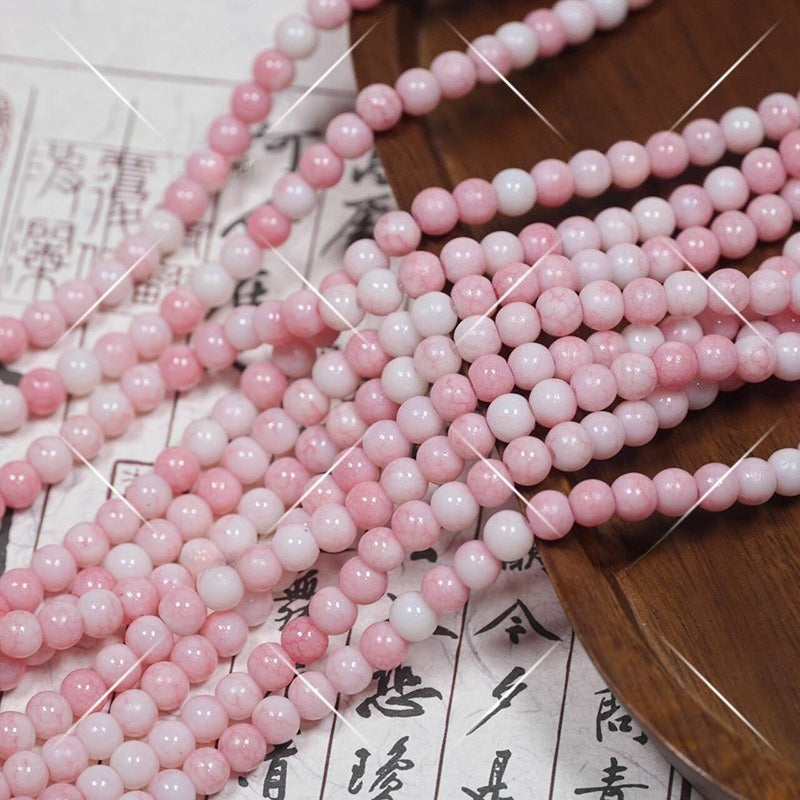 Pink and white marbled round porcelain beads draped over wooden tray