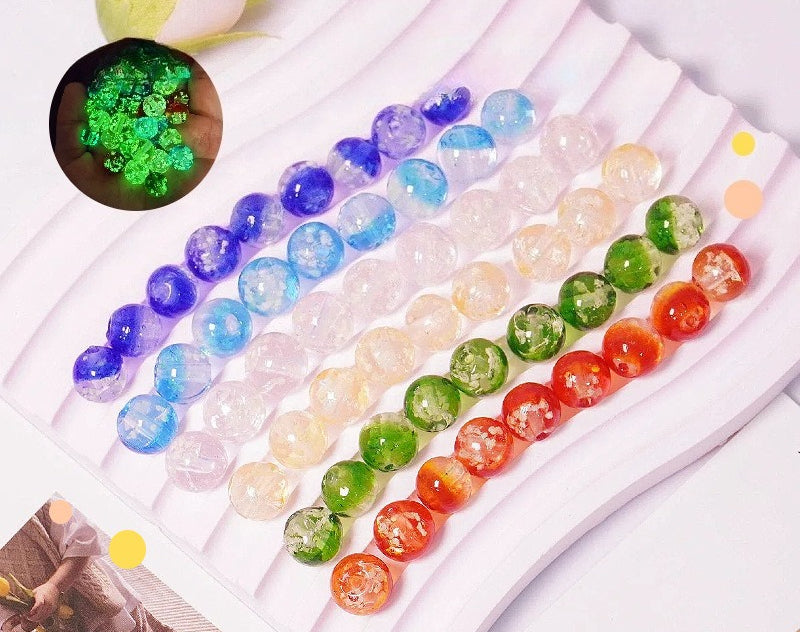 Two-tone glow-in-the-dark glass beads in purple, blue, red and green in a tray, inset shows green glow effect